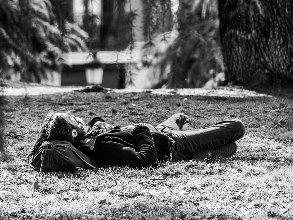 Hombre recostado sobre la hierba mirando al cielo
